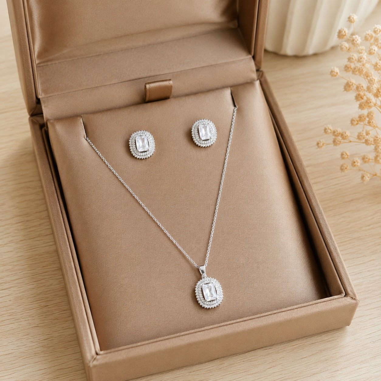 Lucent Frame matching clear zircon pendant and stud earrings displayed in a champagne-tone jewellery box.