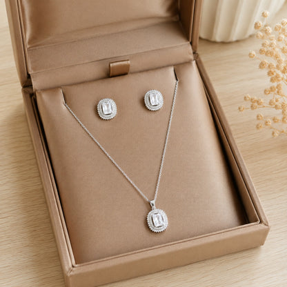 Lucent Frame matching clear zircon pendant and stud earrings displayed in a champagne-tone jewellery box.
