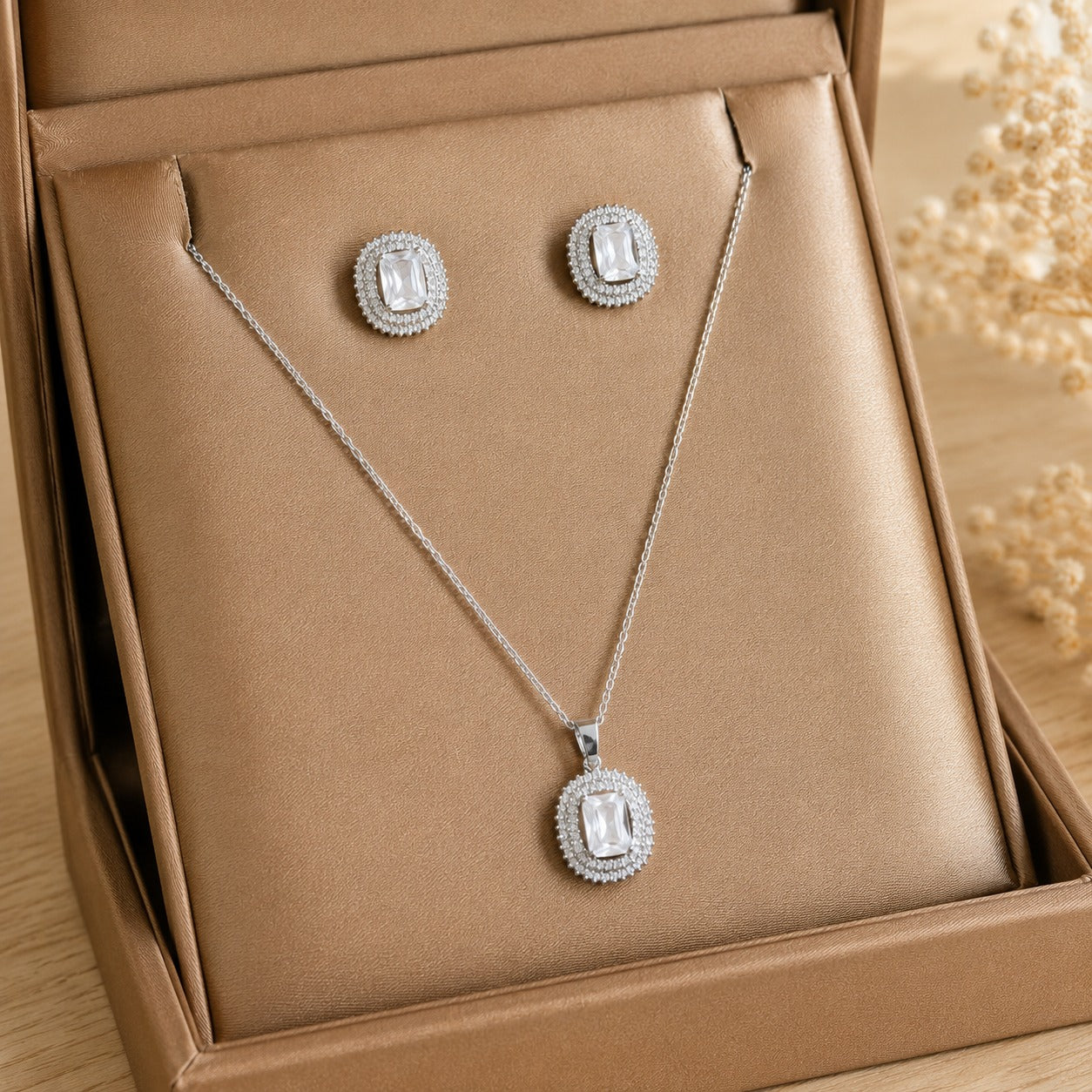 Lucent Frame matching clear zircon pendant and stud earrings displayed in a champagne-tone jewellery box.
