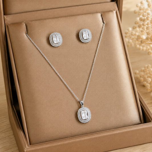 Lucent Frame matching clear zircon pendant and stud earrings displayed in a champagne-tone jewellery box.
