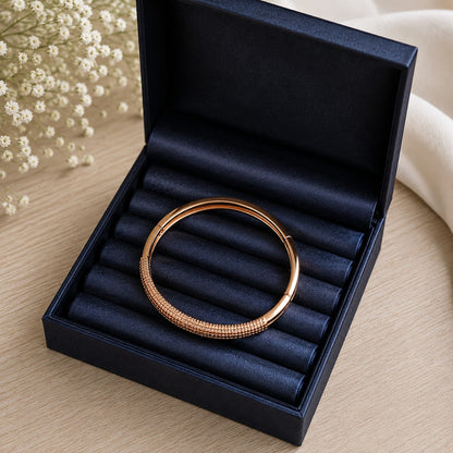 Close-up of Ember Arc rose-gold bracelet in a navy jewellery box, highlighting its textured multi-row front and polished circular band
