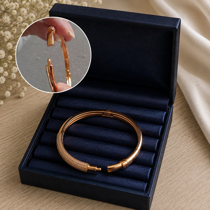Open Ember Arc rose-gold bracelet displayed in a navy jewellery box, showing its opening and closure mechanism.
