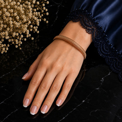 Rose-gold Ember Arc bracelet worn on the wrist with a navy lace-trimmed sleeve against black marble.