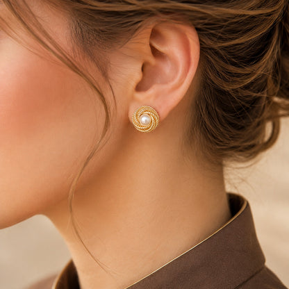  close up ofModel wearing round gold-tone Pearl Coil Studs featuring a luminous pearl centre framed by intricate rope-textured 