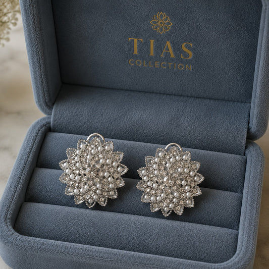 Silver-tone statement clip earrings featuring an intricate radial design embellished with miniature pearls and clear sparkling stones in a box