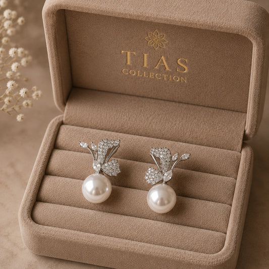 Statement pearl drop earrings featuring sculptural silver-tone curves, sparkling clear zircon and botanical wing-like detailing.
