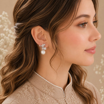 Model wearing silver-tone Pearlwing Earrings featuring clear zircon wing-inspired detailing, marquise accents and luminous round pearl drops.