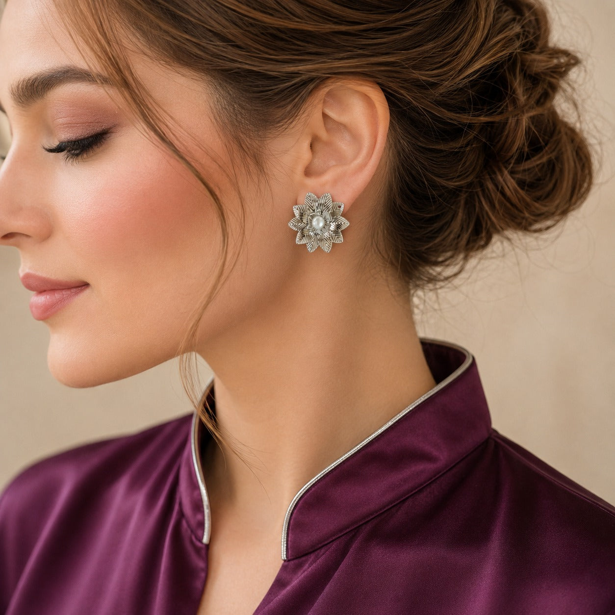 Model wearing Silver Fern silver-tone botanical statement earrings with textured layered leaves and pearl centres.