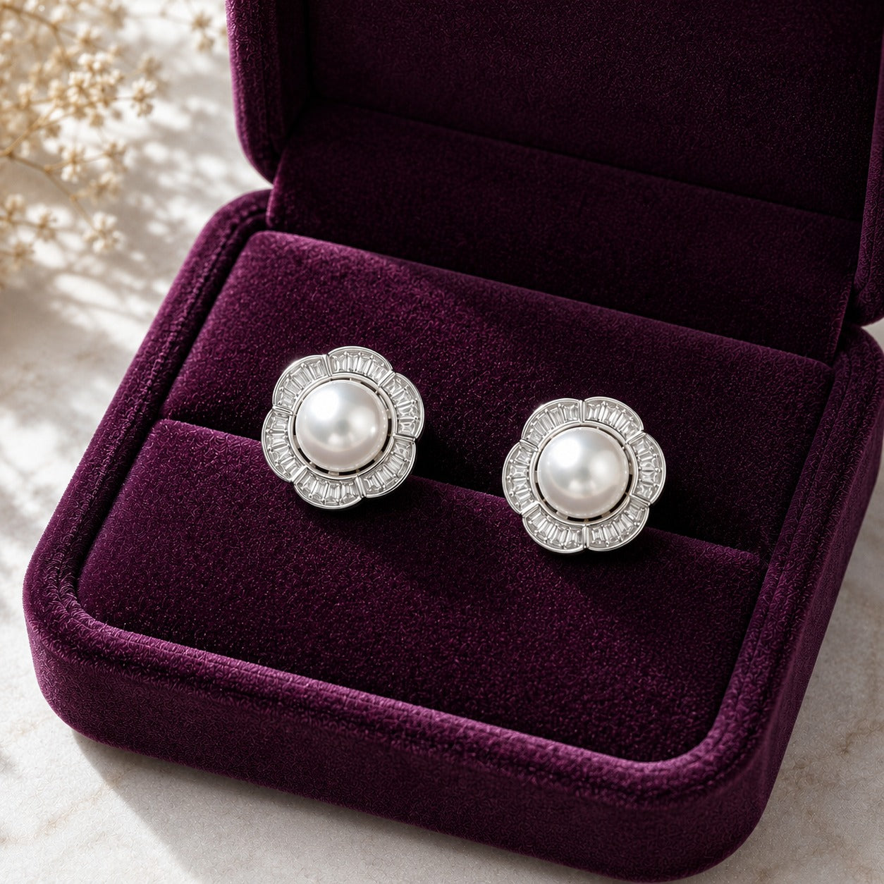 Floral  silver pearl stud earrings featuring a luminous centre pearl surrounded by clear baguette stones