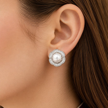 Close up of a model wearing Floral  silver pearl stud earrings featuring a luminous centre pearl surrounded by clear baguette stones