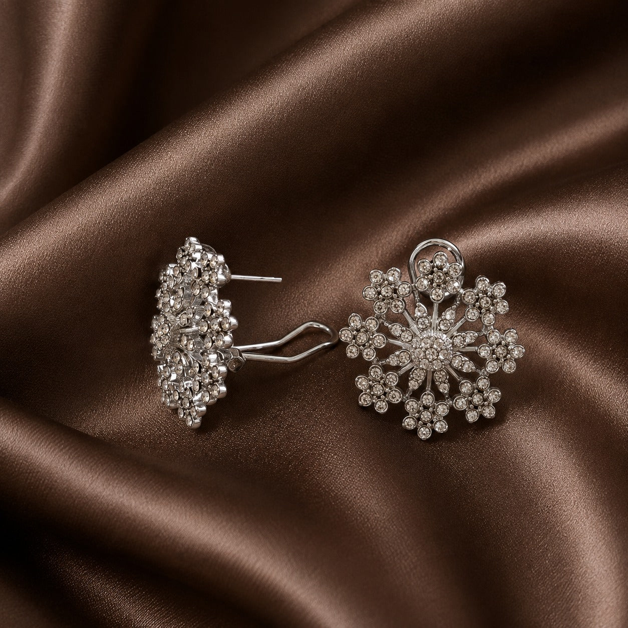 Side view of a silver-tone floral crystal earring showing its dimensional construction, post and distinctive ear-support fitting.