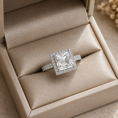 Crystal Clear Square-cut statement ring with faceted centre stone, clear stone halo and detailed band displayed in a champagne jewellery box.