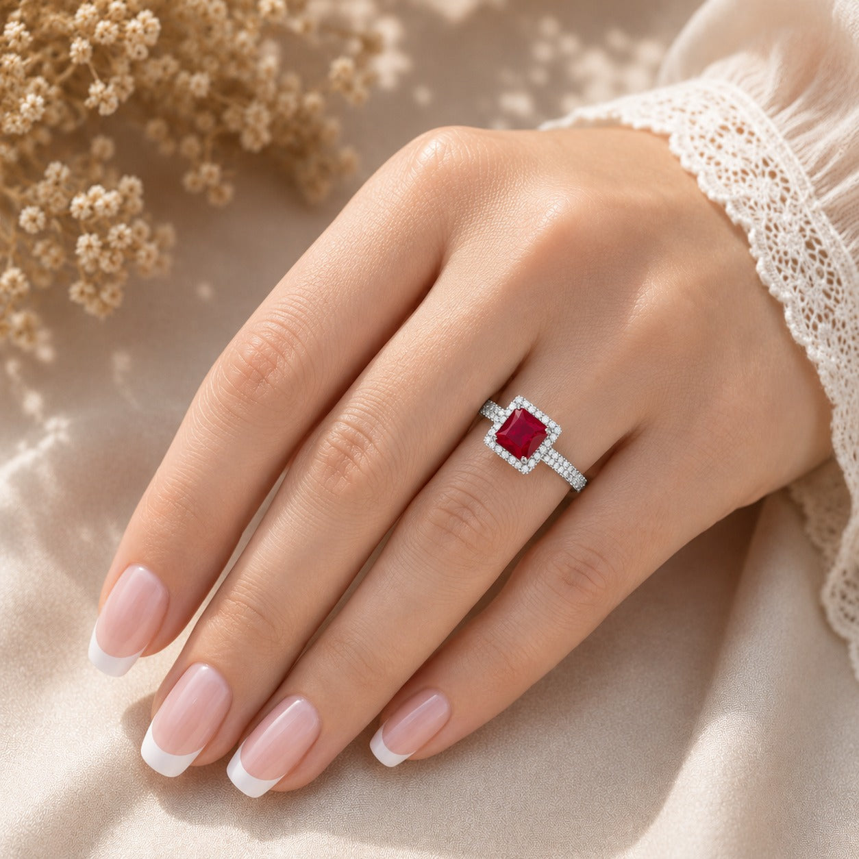  Ruby Red Square-cut statement ring worn on a manicured hand, showcasing the faceted centre stone, sparkling halo and stone-set band