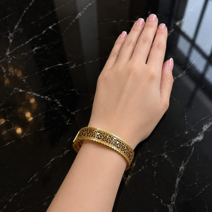 Gold-tone Gilded Lattice Cuff worn on a thin wrist, showing its structured fit and ornate openwork design.