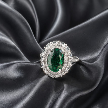 S925 Verdant Oval Ring with a deep emerald-green oval centre stone and clear marquise accents on black satin.