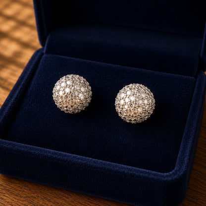 Close-up of silver-tone dome stud earrings featuring intricate lattice openwork and delicate pearly-white detailing.