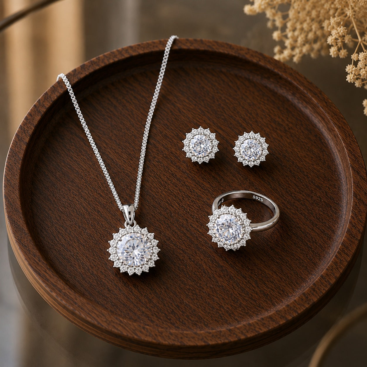 S925 silver earrings, pendant necklace and matching ring set with round clear centre stones and detailed clear stone borders displayed on dark wood.