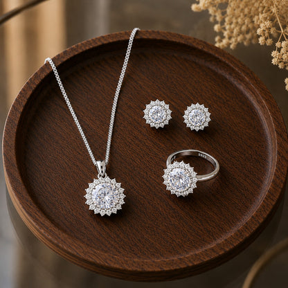 S925 silver earrings, pendant necklace and matching ring set with round clear centre stones and detailed clear stone borders displayed on dark wood.