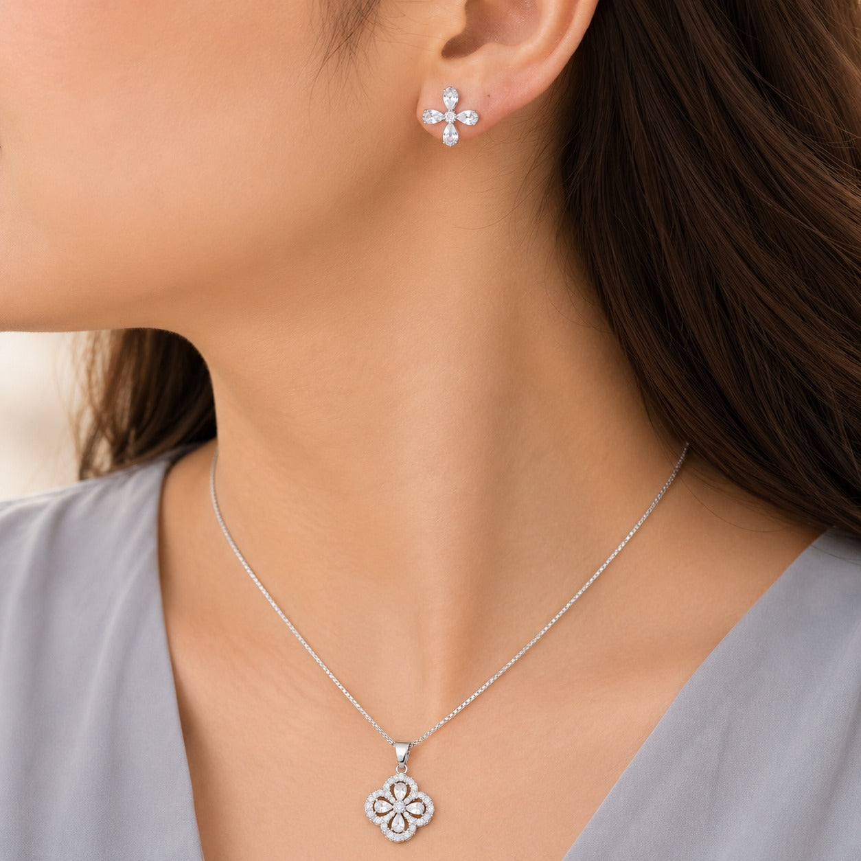Petal Loop S925 silver pendant necklace and matching clear zircon four-petal stud earrings worn with a soft grey outfit.