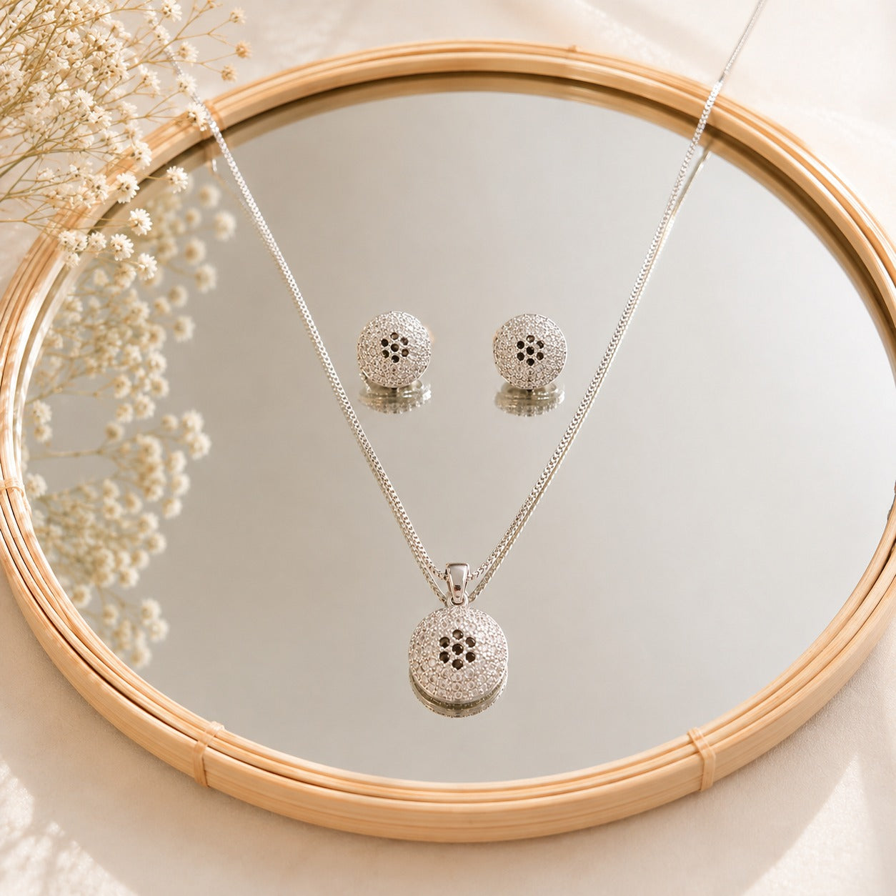 S925 silver Vela Dot earrings and pendant set displayed on a mirror, showcasing the circular textured design and clear zircon detailing.