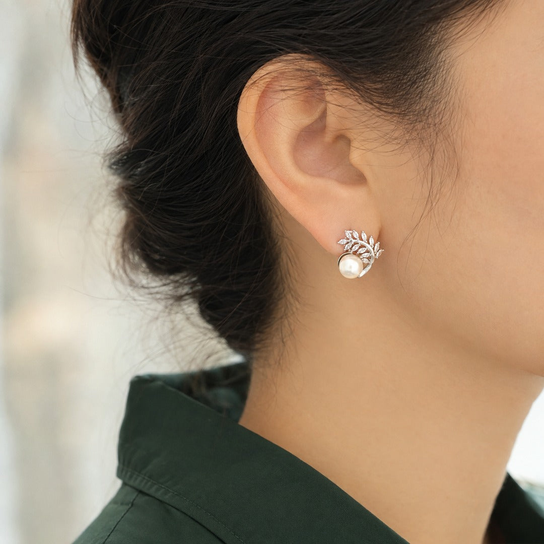 Silver-tone Pearl Arbor Stud earring worn on the ear, featuring a luminous white pearl with curved marquise-cut clear stone leaf detailing.