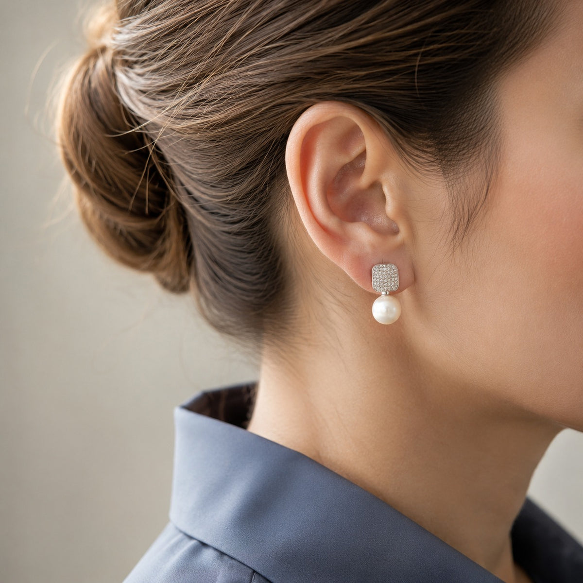Pearl Grid Drop Earring worn on the ear, featuring a crystal-detailed rounded-square top with a smooth white pearl suspended below.