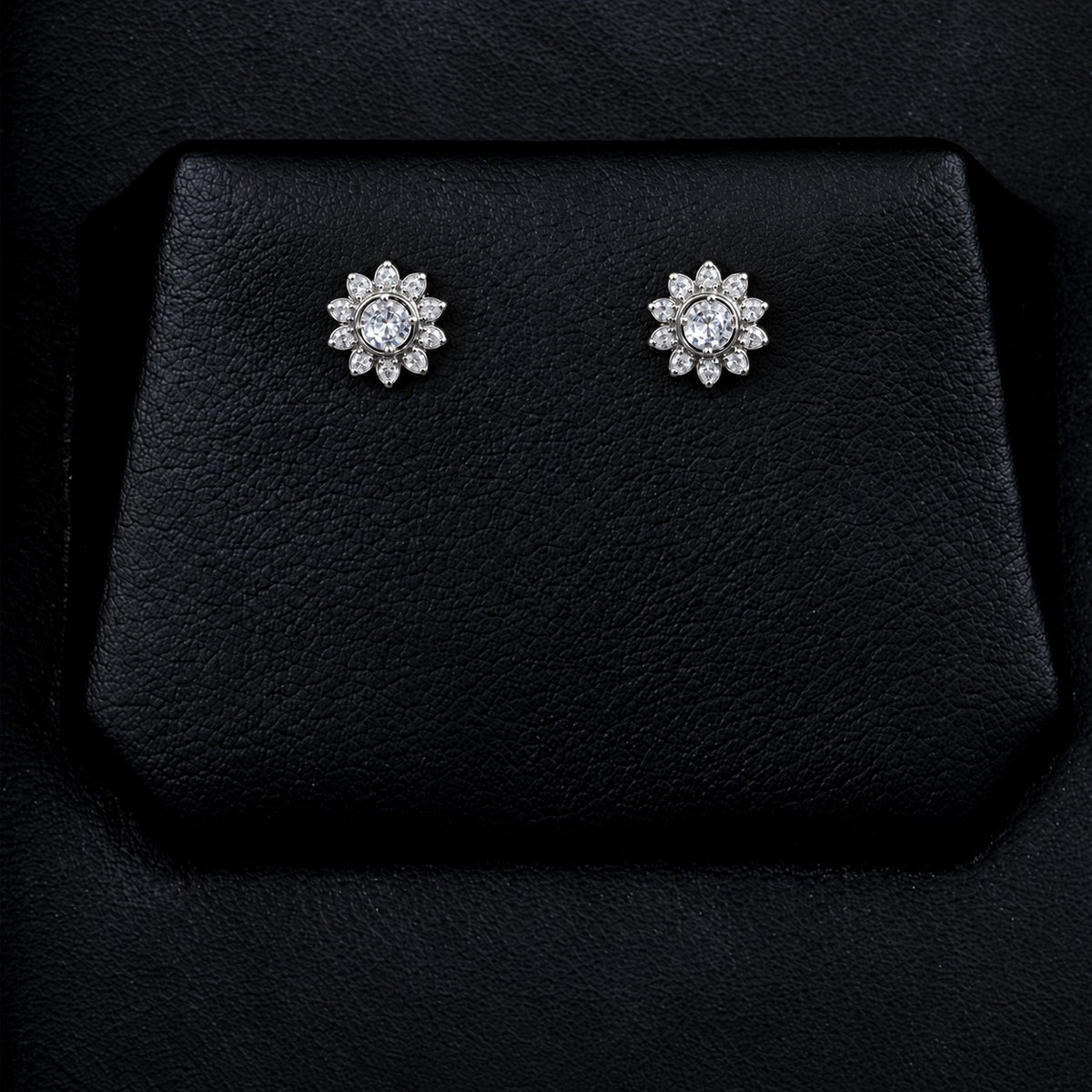 Solaris Crest Stud earrings with round clear zircon centre stones and radiating marquise-cut zircon detailing, displayed on a black jewellery surface.