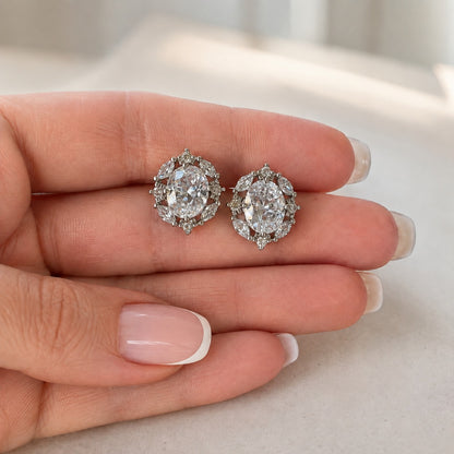 Pair of Lustre Vale S925 silver earrings displayed on a hand, showing oval clear zircon centre stones and detailed marquise-cut zircon framing.