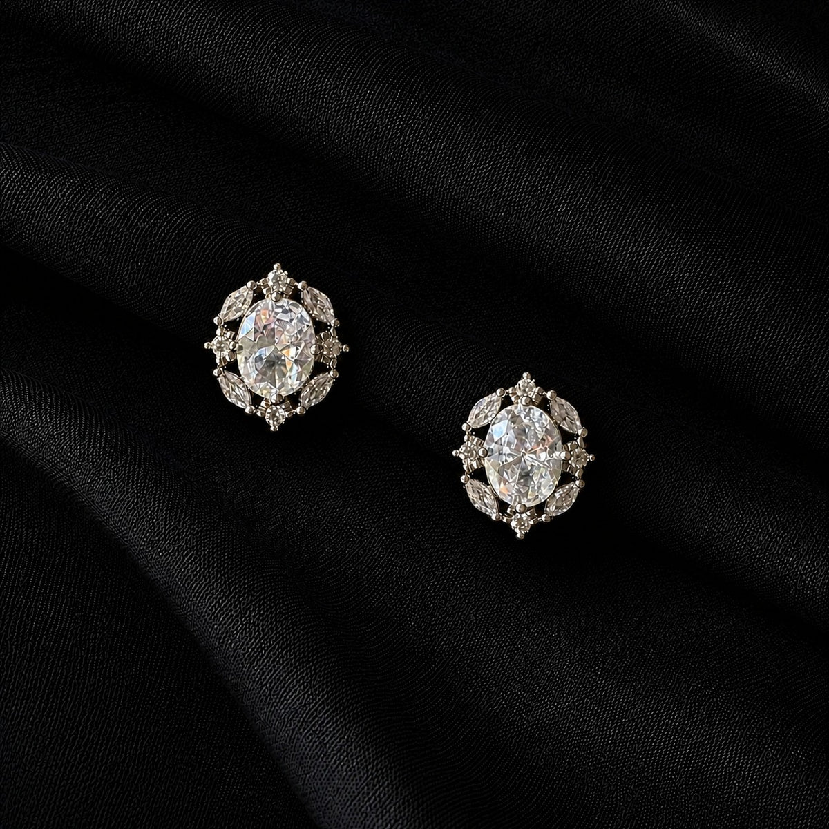 Lustre Vale S925 stud earrings with large oval clear zircon centre stones and marquise-cut zircon accents, displayed on textured black fabric.