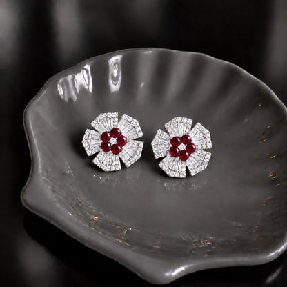 Radiant Crest Stud earrings with clear baguette zircon detailing and red centre stones, displayed on a smoky grey dish.