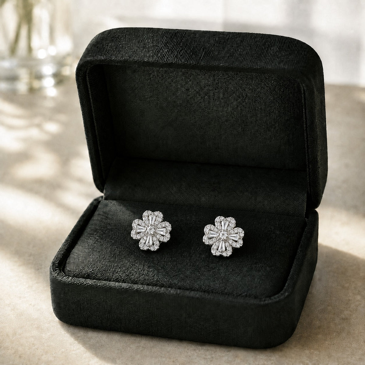 S925 silver Prism Clover Studs displayed in a black jewellery box, featuring four sculpted petals with tapered baguette and clear zircon detailing.