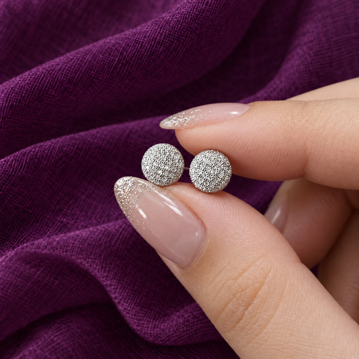 Hand-held close-up showing the compact size and detailed clear zircon finish of the Silver Constellation Studs.