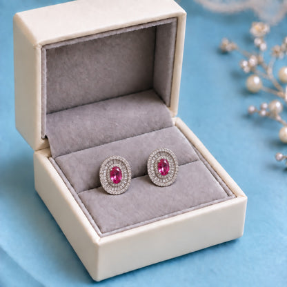 Crownline Oval Studs featuring a faceted oval ruby pink centre crystal framed by baguette-cut and round clear zircon stones in a polished silver-tone setting.