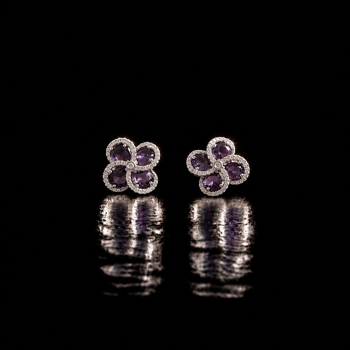 Quadra Halo Stud Earrings with four faceted  purple stones, clear zircon borders and silver-tone setting displayed on a glossy black reflective surface.