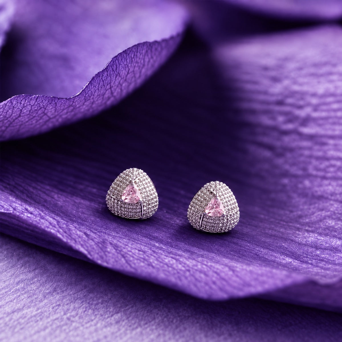 Close-up ear view wearing a triangular coloured stone  light blush pink stud with sparkling clear zircon detailing and a polished silver-tone finish.