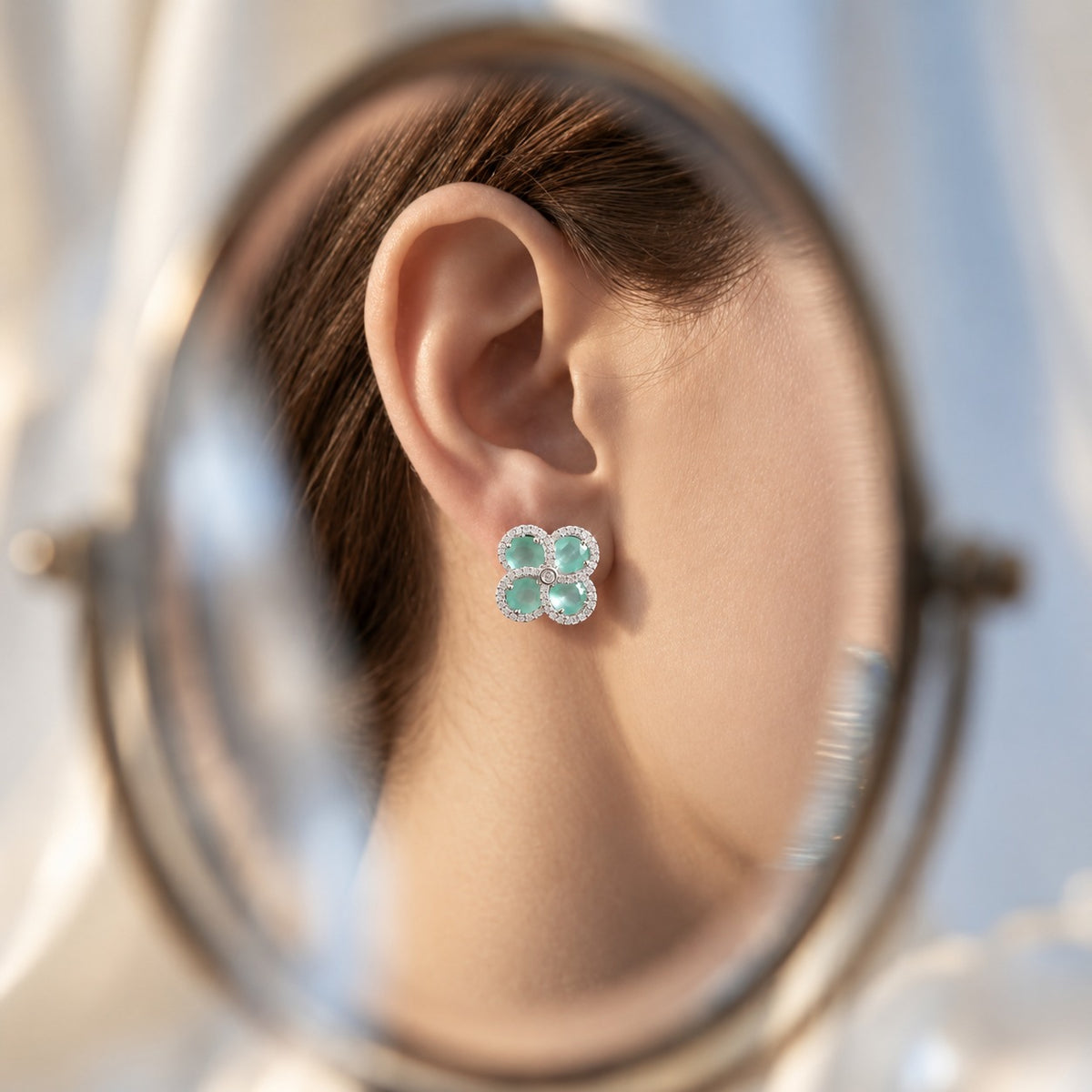 Close-up ear view wearing Quadra Halo Stud Earrings, showing the four-petal  mint aqua stone design and sparkling clear zircon detailing