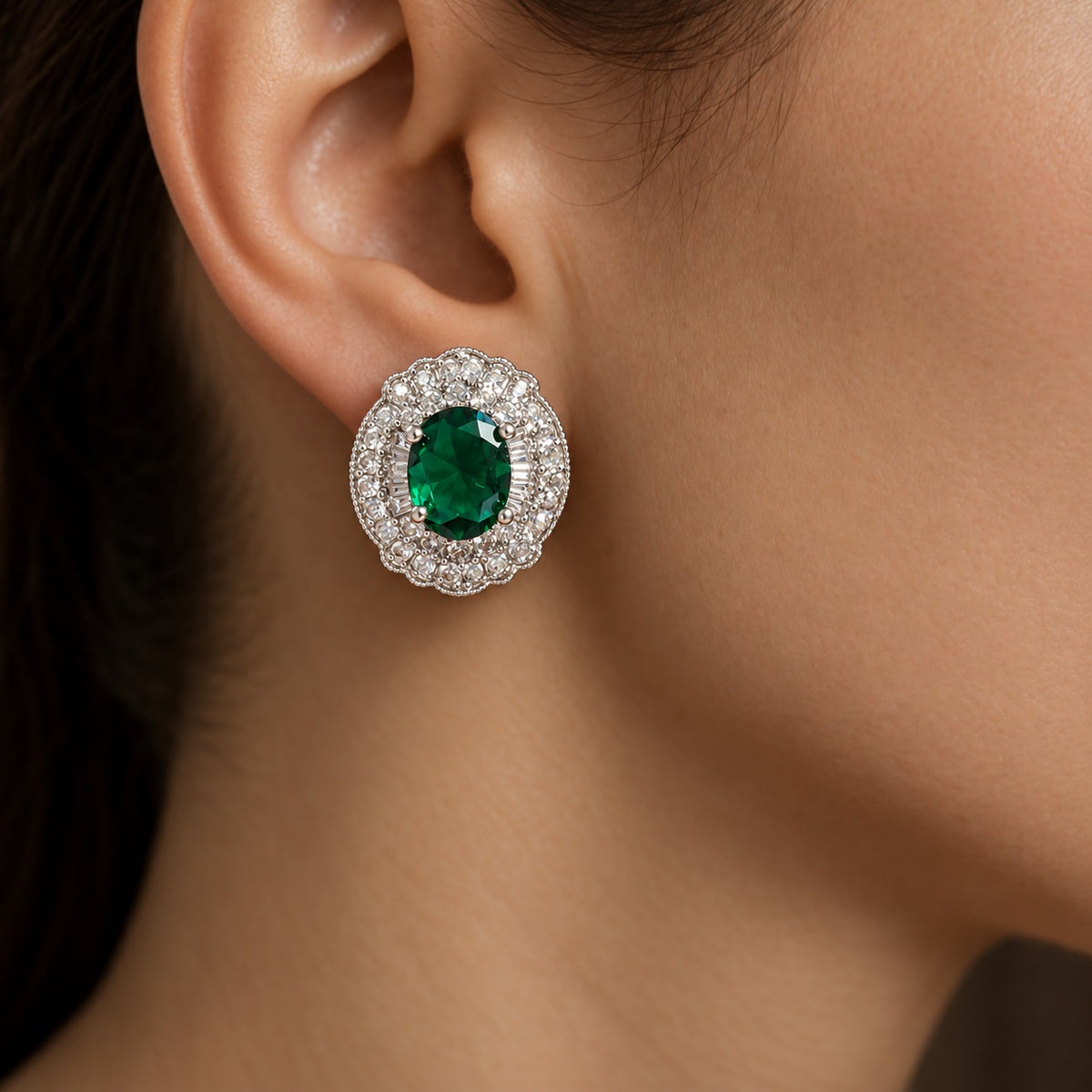 Close-up of Verdanza Oval Stud worn on the ear, featuring an emerald green oval centre stone surrounded by intricate clear zircon detailing.