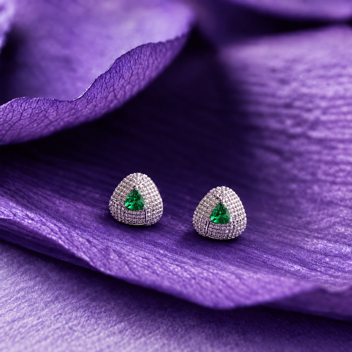 Close-up ear view wearing a triangular emerald green stone stud with sparkling clear zircon detailing and a polished silver-tone finish.