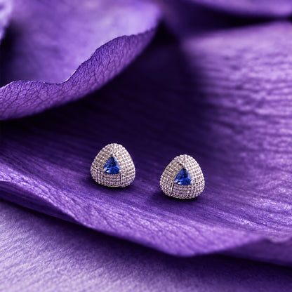Close-up ear view wearing a triangular sapphire blue stone stud with sparkling clear zircon detailing and a polished silver-tone finish.