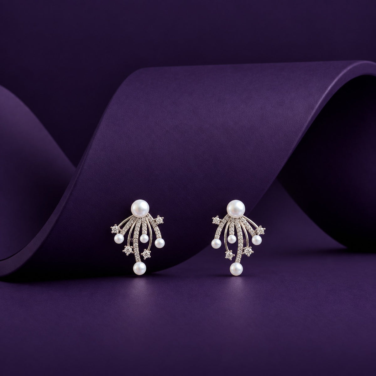 Pearl Drift Stud Earrings with white pearls, curved silver-tone strands and delicate clear zircon accents displayed on a deep purple background.