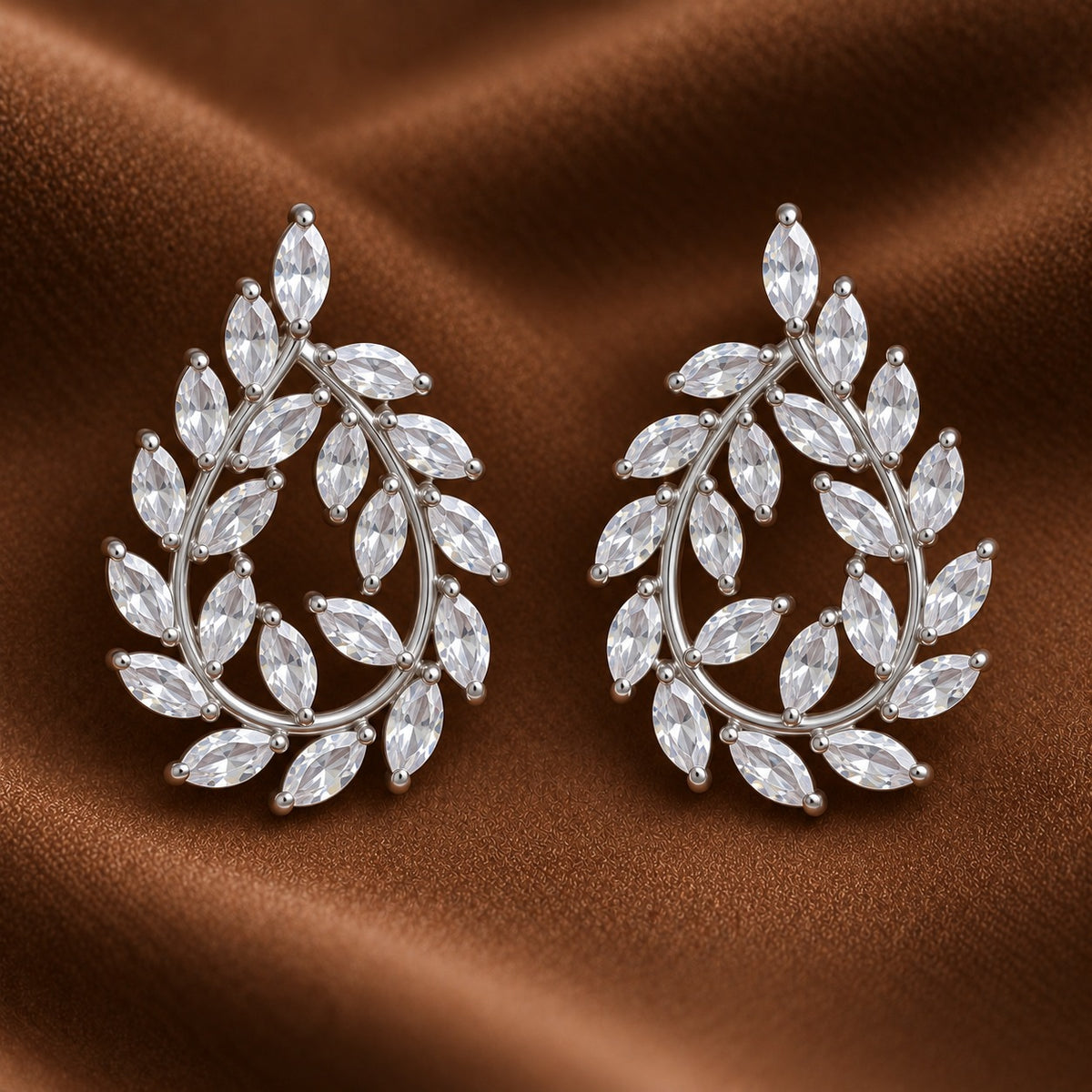 Close up of silver Laurel Drop Earrings featuring marquise-cut clear zircon leaves arranged around an open teardrop-shaped silver-tone frame.
