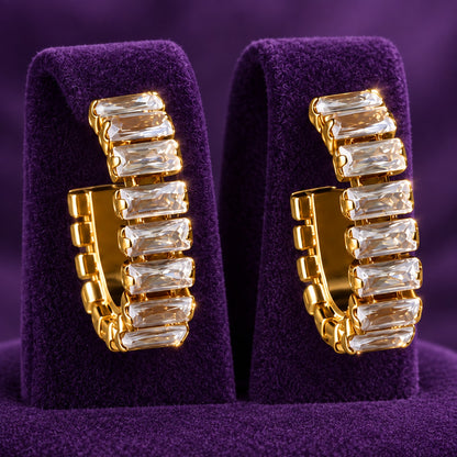 Close-up of geometric hoop earrings featuring individually set rectangular clear zircon stones in gold