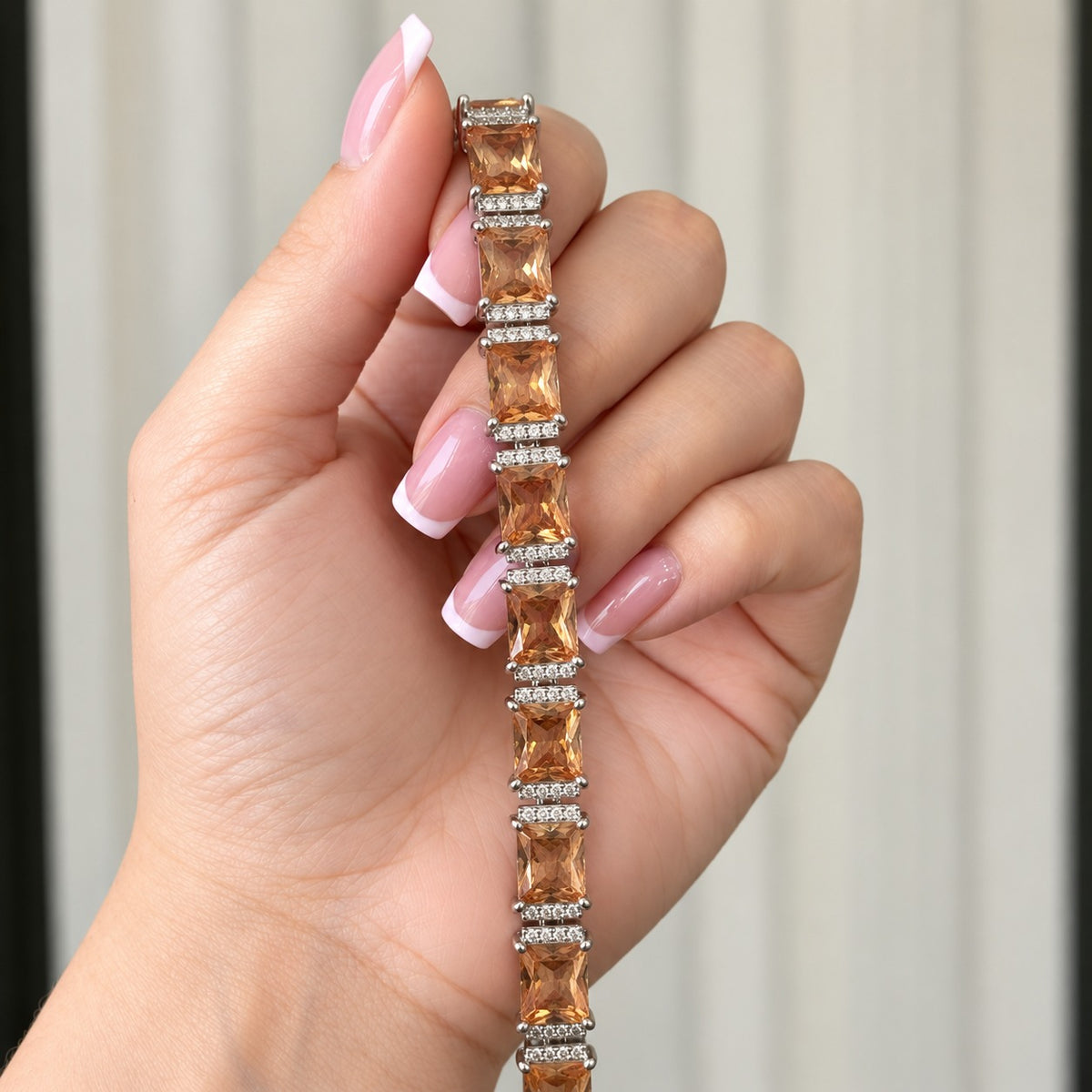 Champagne Gallery Link Bracelet held vertically in a French-manicured hand, showing the rectangular stone links and zircon detailin
