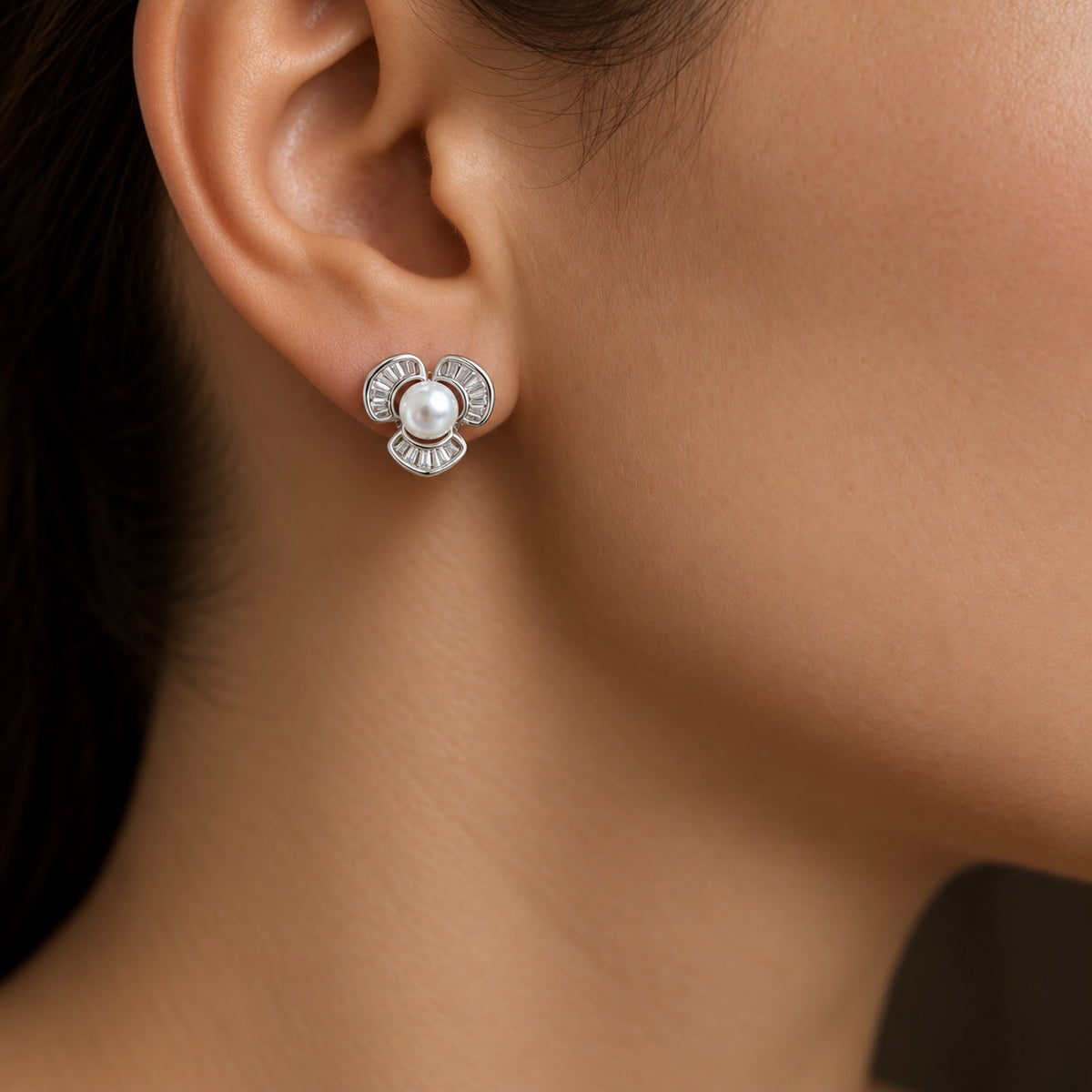 Close-up of a woman wearing a compact Pearl Arc Stud Earring with a white pearl centre and three curved silver-tone sections detailed with clear baguette stones