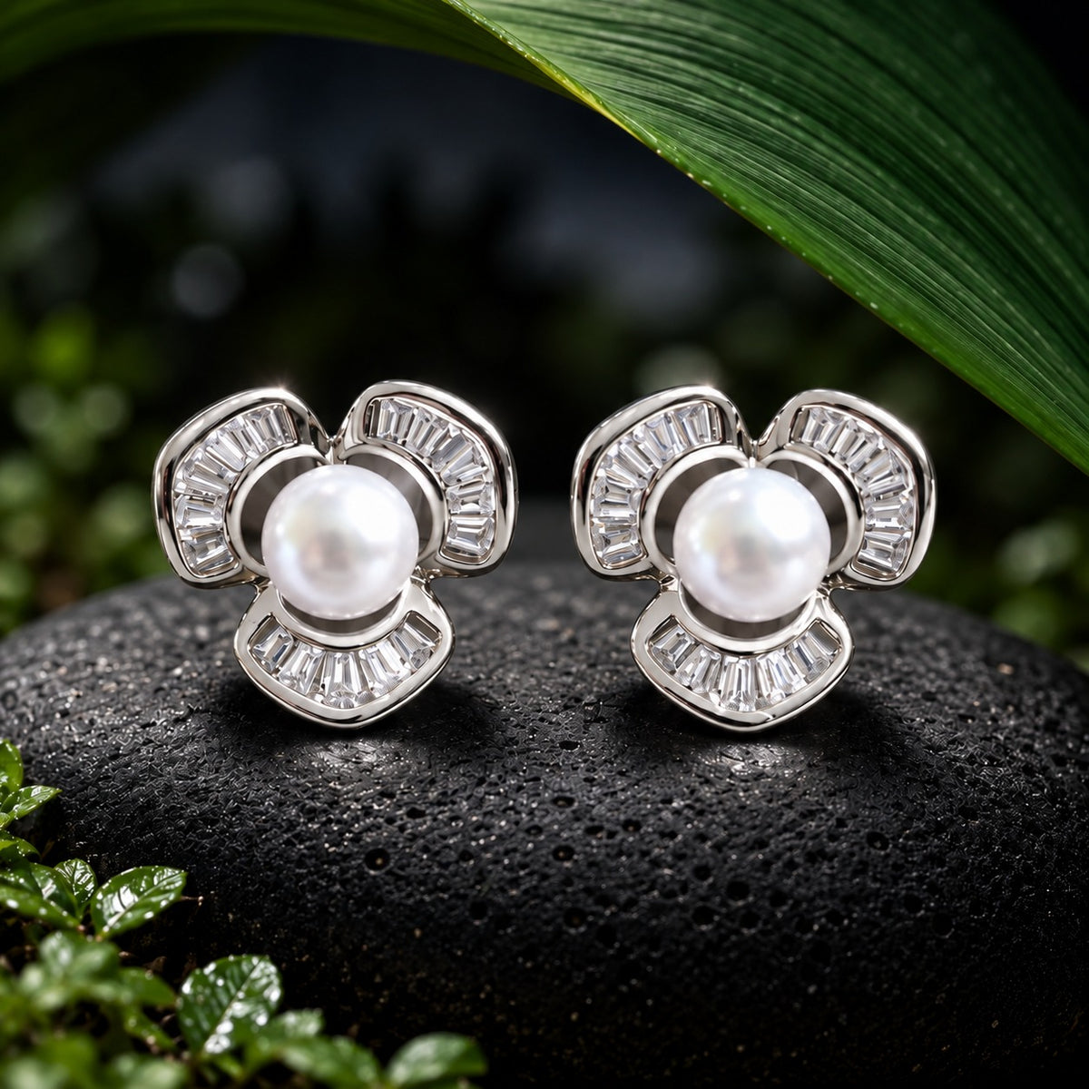Close-up of Pearl Arc Stud Earrings featuring round white pearls surrounded by three silver-tone curved sections set with clear baguette stones on a black textured surface