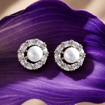 Pearl Circuit silver-tone stud earrings featuring round white pearl centres surrounded by a circular frame of clear faceted stones on a deep purple surfac
