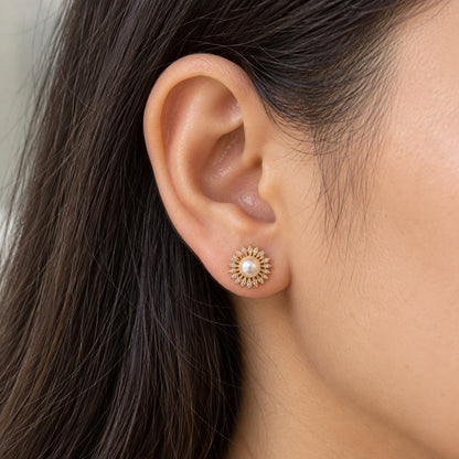 Woman wearing a compact gold-tone Pearl Sunray Stud Earring with a central white pearl and symmetrical ring of clear marquise stones.