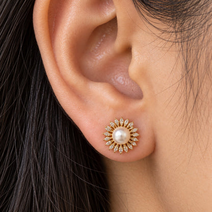 Close-up of a gold Pearl Sunray Stud Earring worn on the earlobe, featuring a white pearl centre encircled by fine marquise-cut clear stones