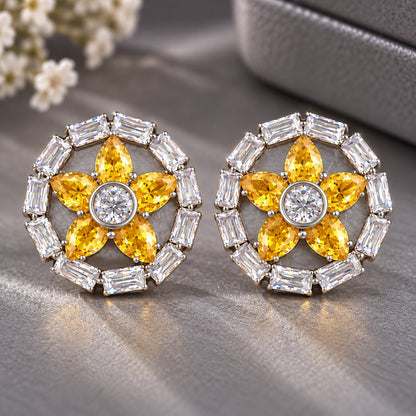 Petal Circuit Stud Earrings featuring five sun yellow pear-cut coloured gemstone petals, a round clear zircon centre and a circular border of clear baguette stones in silver-tone metal.”
