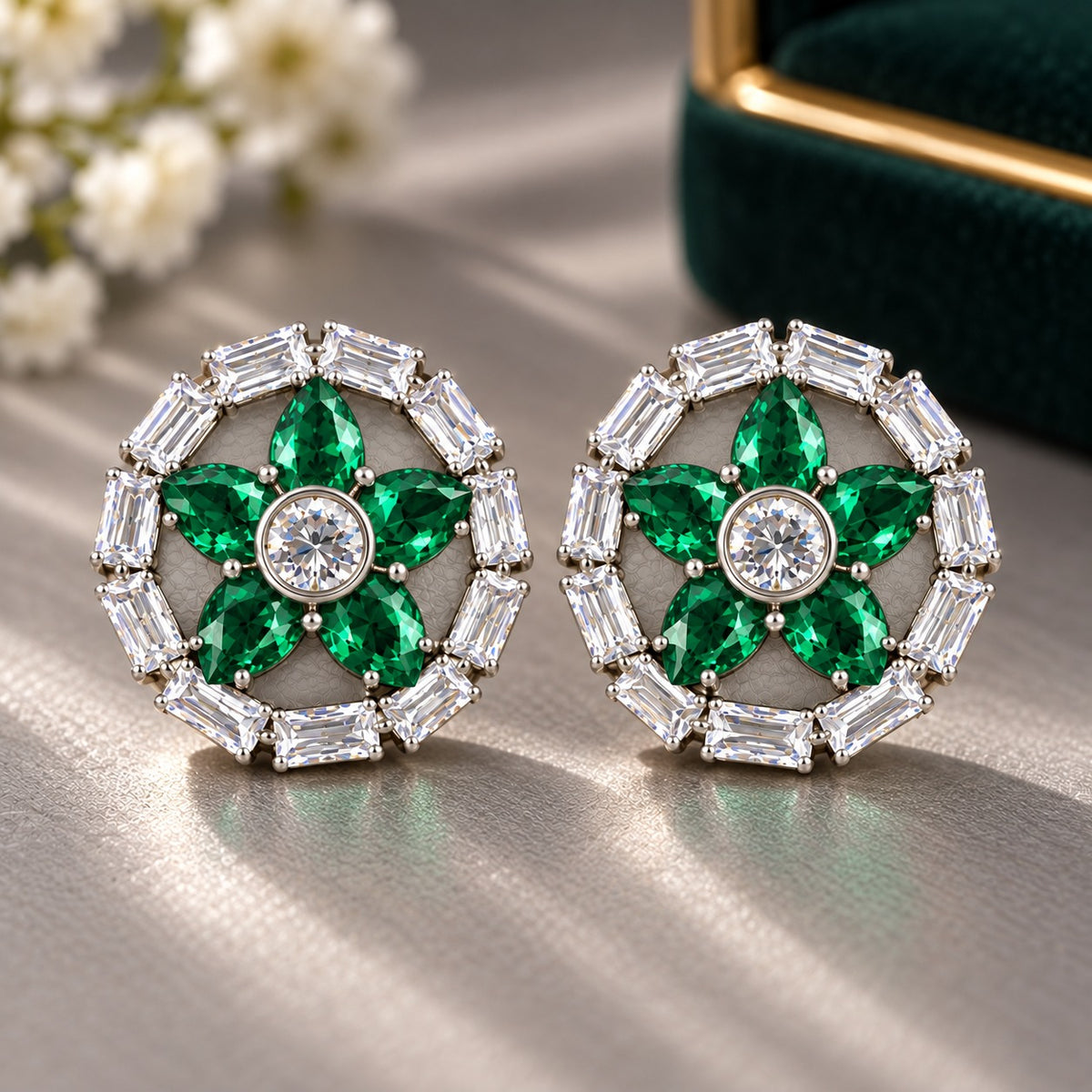Petal Circuit Stud Earrings featuring five  emerald green pear-cut coloured gemstone petals, a round clear zircon centre and a circular border of clear baguette stones in silver-tone metal.